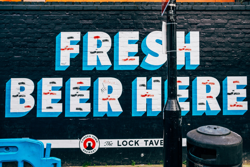 Auf Wand gemalte Schrift "Fresh Beer Here" (Samuel Regan auf Unsplash)