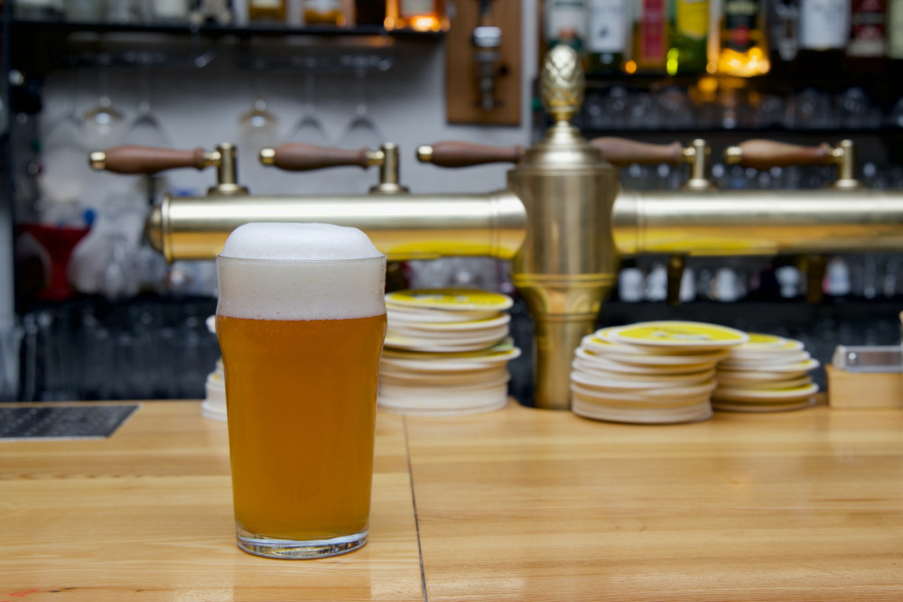 Ein helles, unfiltriertes Bier im Glas auf einem Bartresen (Bohdan Stocek auf Unsplash)